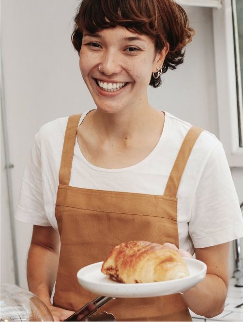 Empleada cafeteria ofrece croissant
